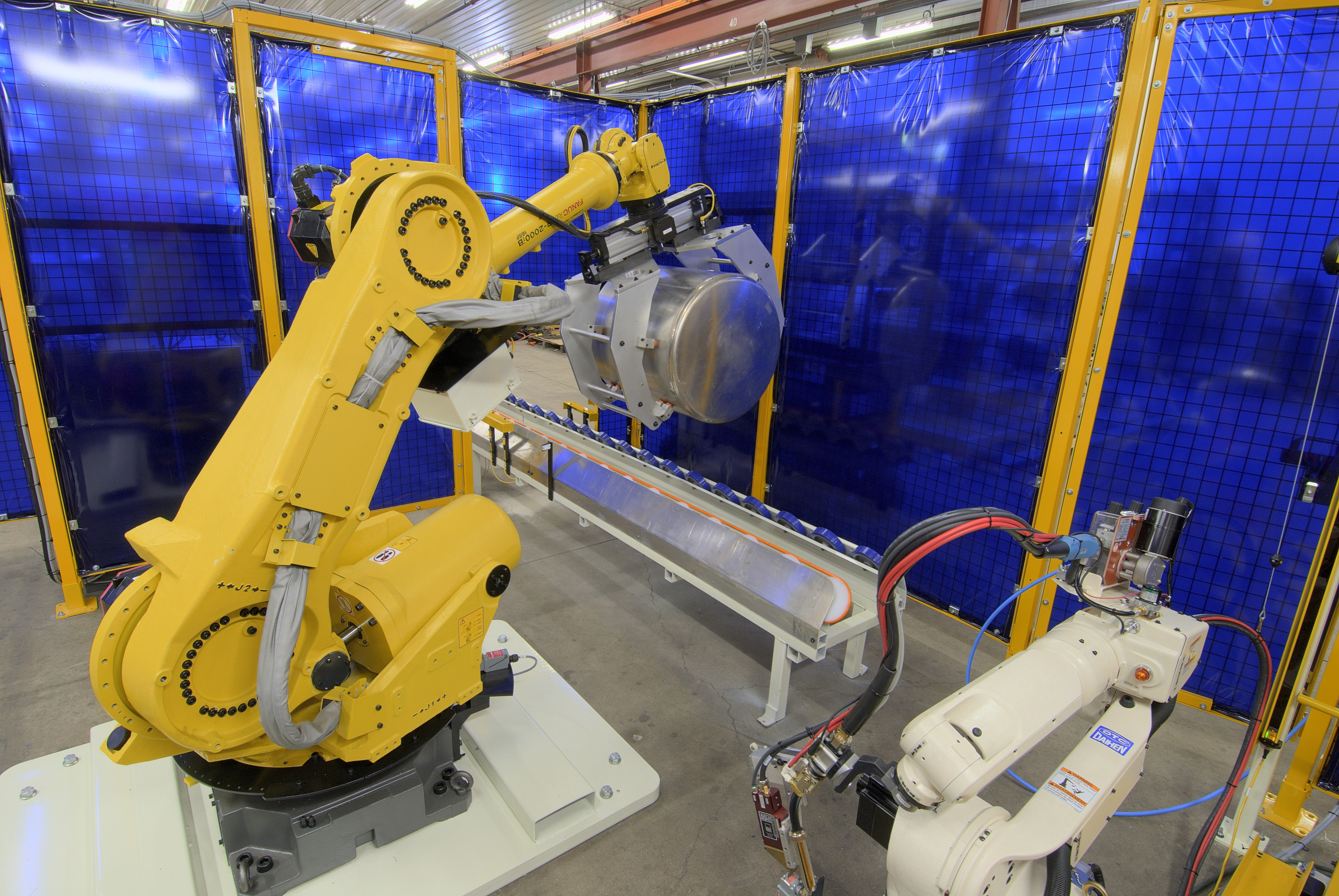 This material handling robot is doing some heavy lifting that would be difficult for a person.  But robots and people can and do work together.  Keep if safe using multiple methods to maintain a safe distance between industrial robots and humans.