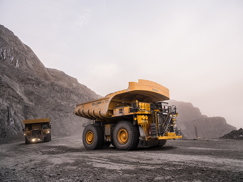 Two autonomous trucks on mine road.