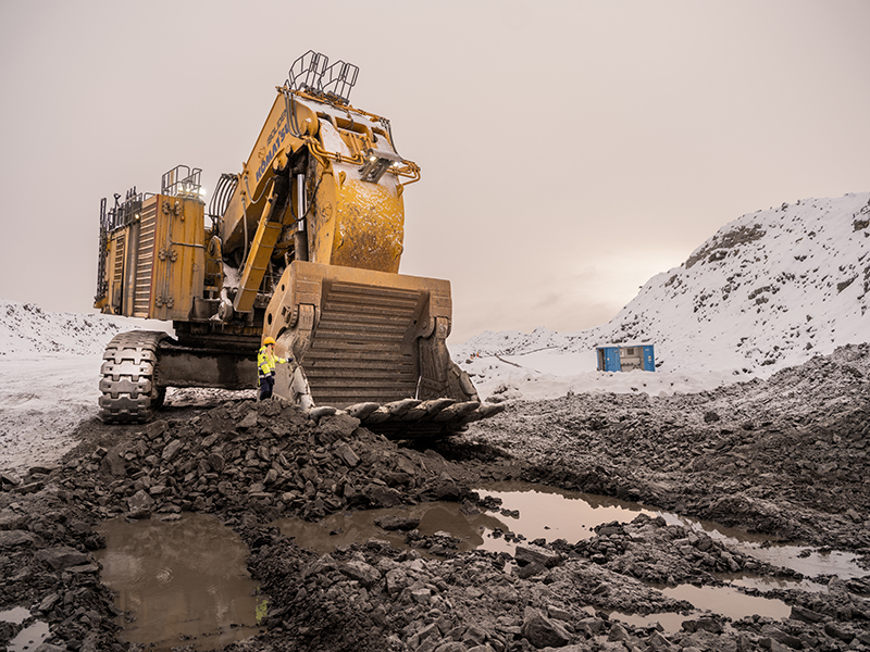 Shovel machine with shovel operator stood next to it