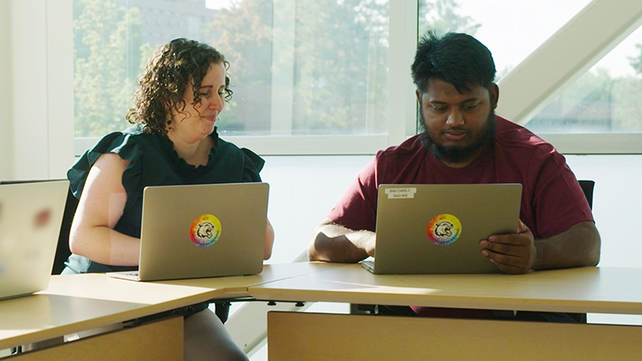 Two people with laptops in a learning environment