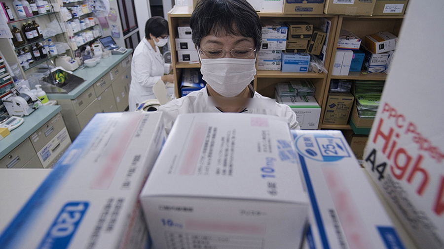 A masked person in a pharmacy with personal protection equipment.
