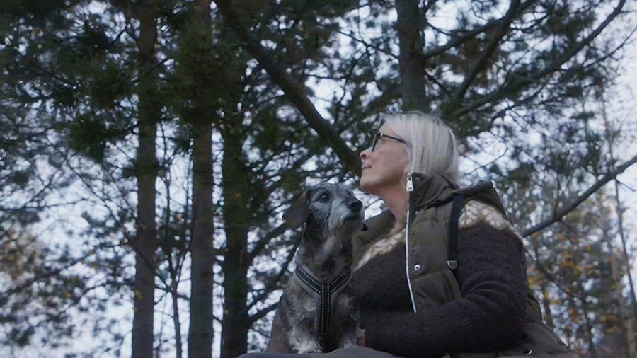 A woman and her dog in a forest.