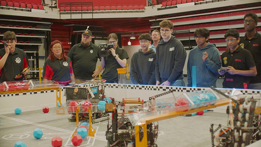 A group of teens and adults at a robotics competition.