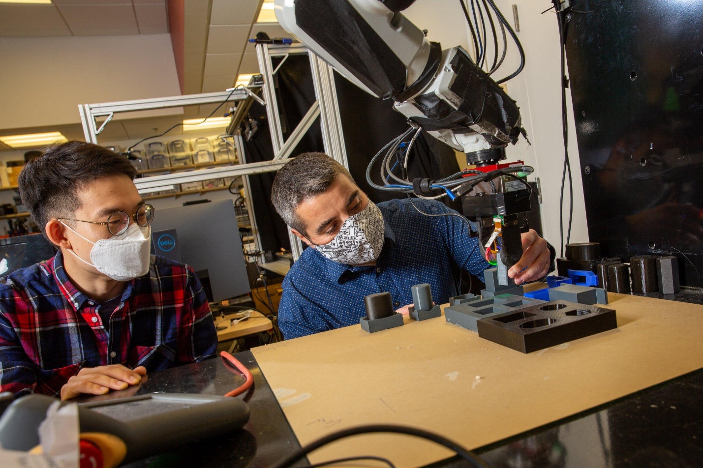 two individuals working with a robot arm