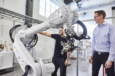 Two men observing a large robot