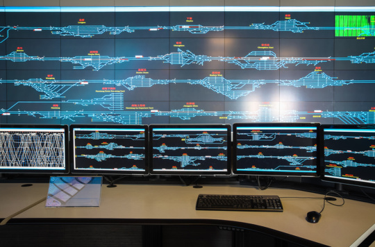 An image of a railway control room with monitors displaying a full rail system.