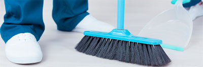 An image of a cleaning crew sweeping into a dust pan