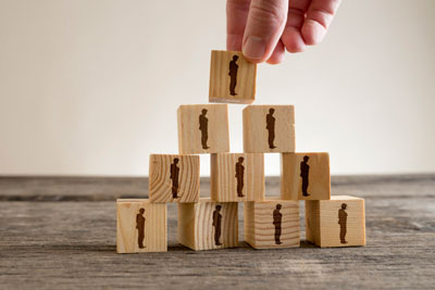 Man stacking a tower of wood blocks with human silhouettes, human resources and management concept.