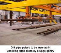 Drill pipe poised to be inserted in upsetting forge press by a Sage gantry